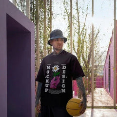 Homme portant un t-shirt imprimé et bob noir, tenant un ballon de basket, dans un décor violet moderne.