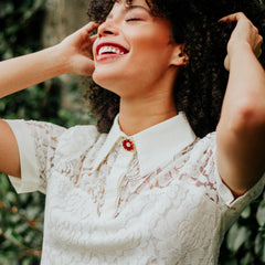 Femme souriante portant une robe en dentelle blanche, mode élégante en extérieur verdoyant