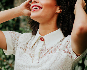 Femme souriante portant une robe en dentelle blanche, mode élégante en extérieur verdoyant
