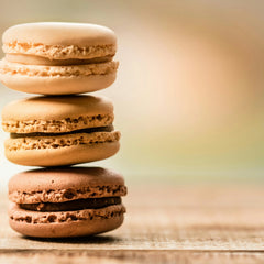 Trois macarons colorés empilés sur une table en bois, gourmandises pâtisserie française.