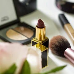 Rouge à lèvres luxe bordeaux, palette maquillage, pinceau et accessoires beauté sur une table