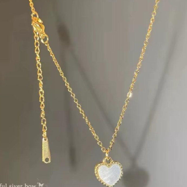 Collier doré chaîne fine avec pendentif cœur blanc pour femme, accessoire élégant.