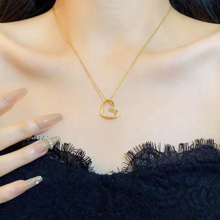 Collier pendentif cœur doré porté avec une robe noire en dentelle, bijou élégant femme