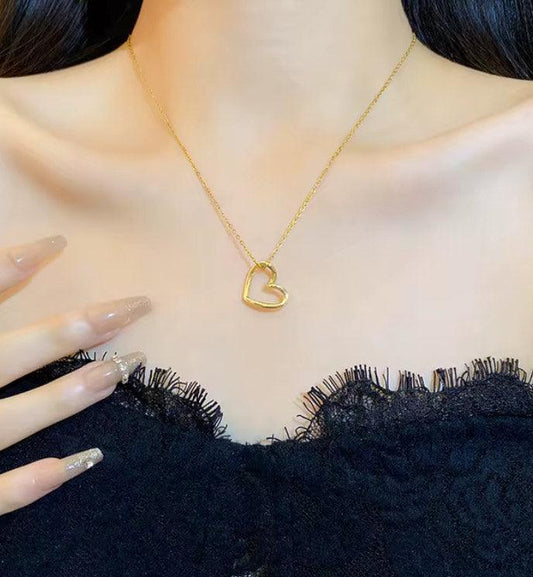 Collier pendentif cœur doré porté avec une robe noire en dentelle, bijou élégant femme