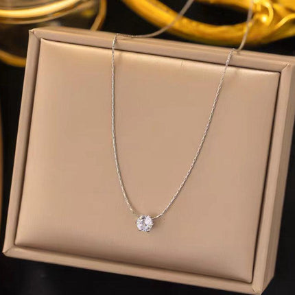Collier fin argenté avec pendentif solitaire rond brillant, présenté sur écrin beige.