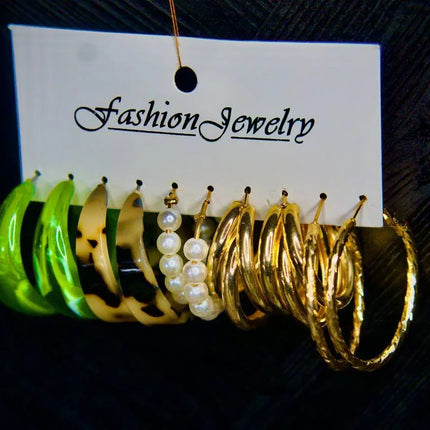 Ensemble de boucles d’oreilles fantaisie dorées, perles, résine verte et léopard sur support.