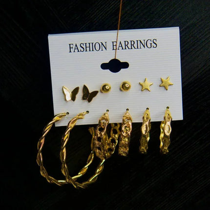 Set de boucles d’oreilles dorées motifs papillon, étoile et créoles sur fond noir