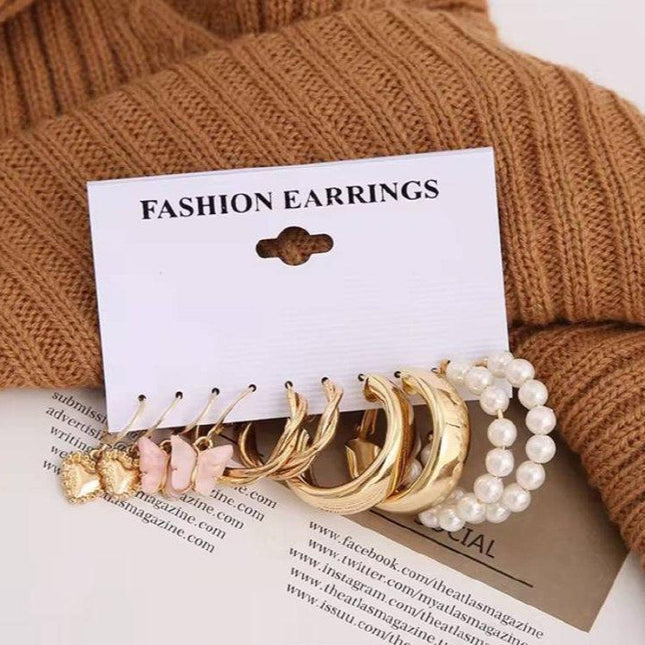 Lot de boucles d’oreilles fantaisie dorées et perles, présentation élégante sur fond beige