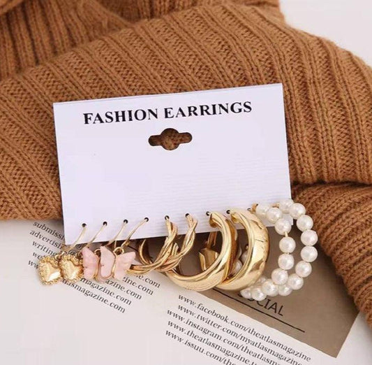 Lot de boucles d’oreilles fantaisie dorées et perles, présentation élégante sur fond beige