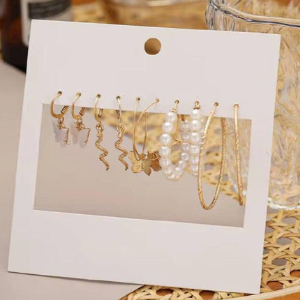 Lot de boucles d’oreilles dorées et perles pour femme, présentées sur support blanc élégant
