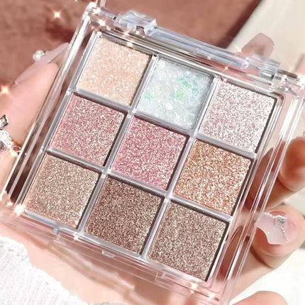 Palette de fards à paupières pailletés rose, nude et doré tenue à la main, maquillage beauté