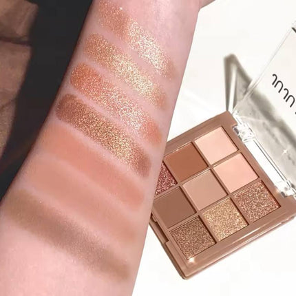 Palette de fards à paupières nude et dorés, swatchs scintillants sur le bras