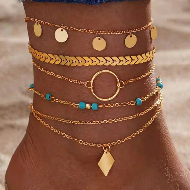 Cheville ornée de bracelets dorés fantaisie et perles turquoise, style plage tendance.