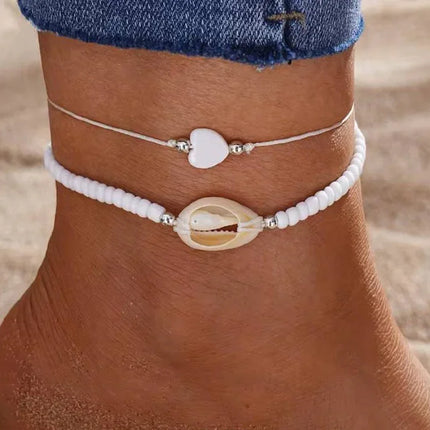 Cheville ornée de bracelets d’été, perles blanches et coquillage, bijou plage tendance femme.