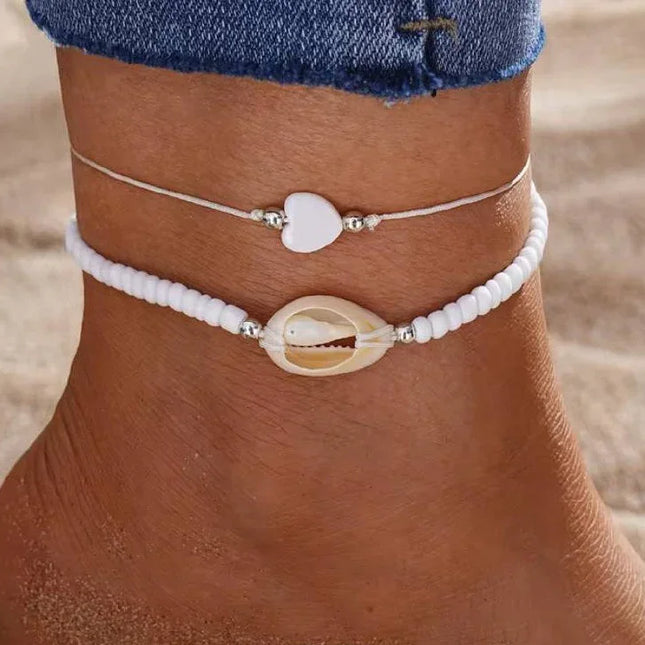 Cheville ornée de bracelets d’été, perles blanches et coquillage, bijou plage tendance femme.