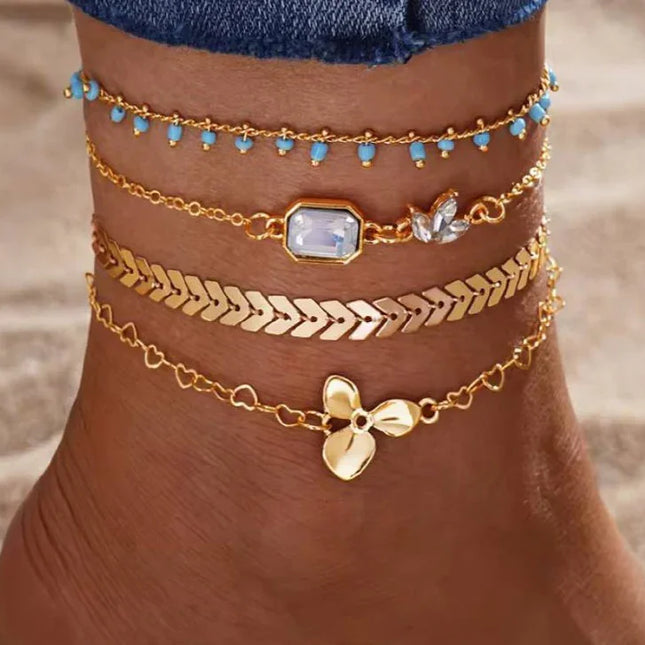 Cheville ornée de bracelets dorés tendance avec perles turquoise et pendentifs mode femme